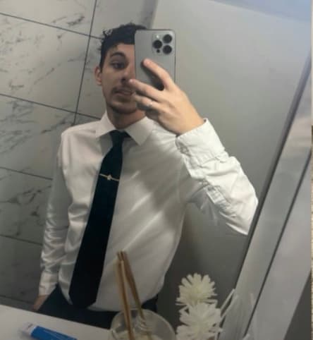 Gustavo Queiroz de camisa branca e gravata, numa selfie no espelho.
